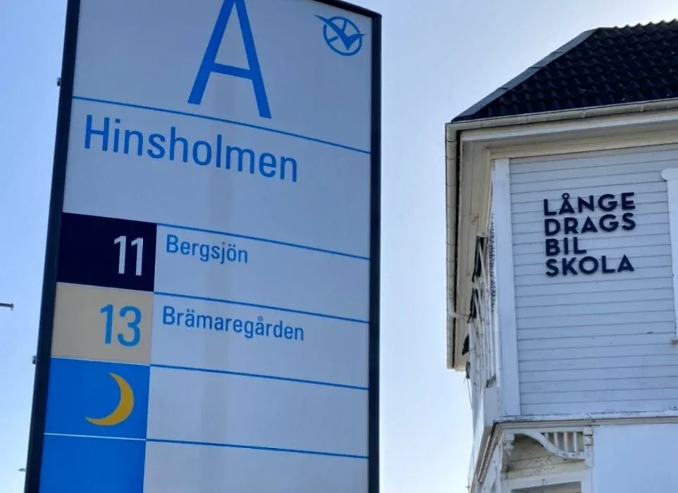 Hållplatsskylten vid Hinsholmen med Långedrags Bilskolas skylt på huset intill
