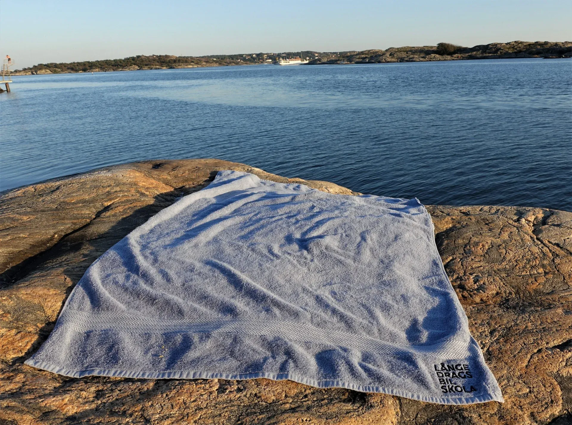 Badlakan med Långedrags Bilskolas logotyp på en klippa vid havet
